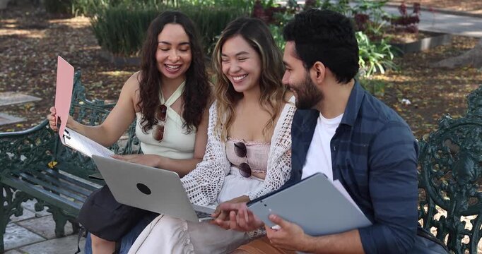 group of young latin friends using laptop, working and having fun in city street in Mexico Latin America at summer season