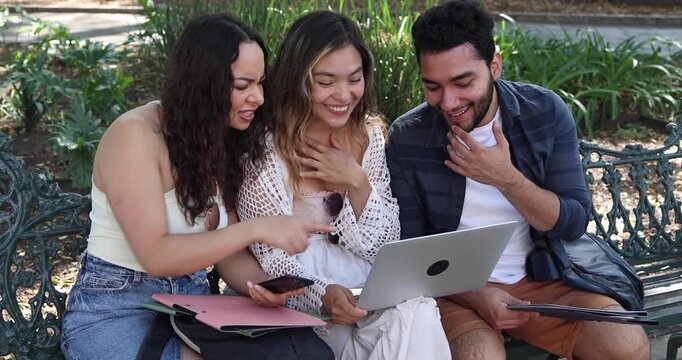 group of young latin friends using laptop, working and having fun in city street in Mexico Latin America at summer season