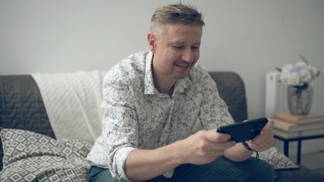 Young Man Playing Game On Smartphone Racing At Home