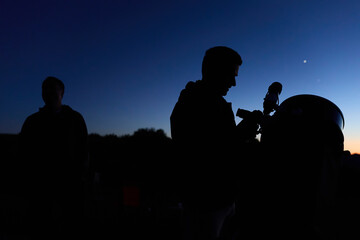Amateur astronomers observing stars, planets, Moon and other celestial objects with a telescope in nature. © astrosystem
