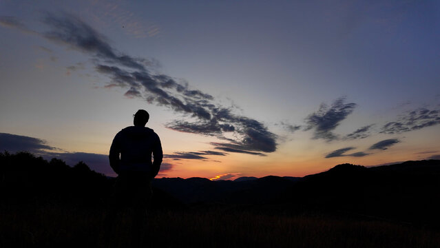Silhouette of a man looking at the mountain sunset.