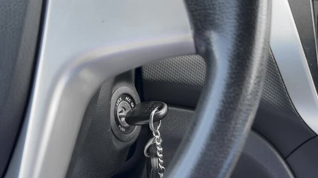 Close-up of a car key inserted into the ignition switch near the steering wheel, ready to start the vehicle.