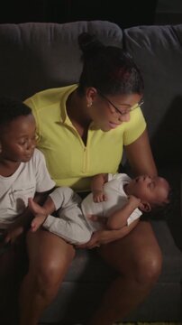Mother cradling newborn with son on couch
