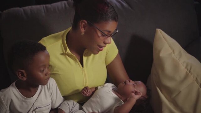 Loving mother holding newborn baby with son