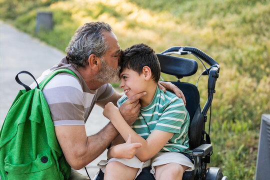 Grandfather kissing child with cerebral palsy on forehead