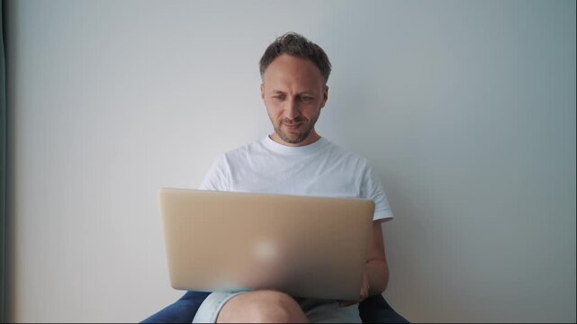 Smiling remote professional reacts to positive news on laptop, suggesting client approval, online learning success, fintech access, or productive hotel work.