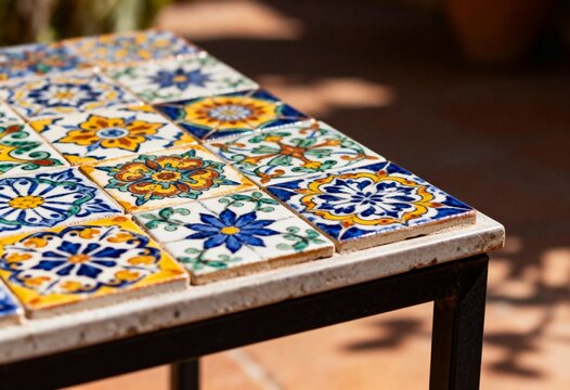 Close up of a Mediterranean style table with hand painted ceramic tiles. Traditional Talavera pattern on outdoor patio furniture. Artisanal mosaic design with floral and geometric motifs