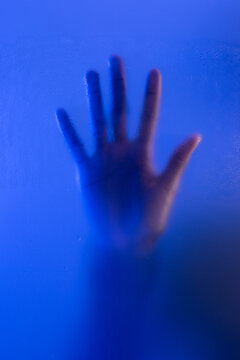 Hand on frosted glass. Anonymous woman reaching out for help concept