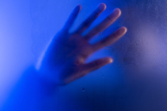 Woman touching wet matte glass in studio. Anonymity and mental issues concept
