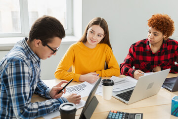 Fototapeta premium Teamwork brainstorm. Diverse colleagues working together discuss financial statistics. Group of happy young modern people sitting in creative office discussing business. Young professional team