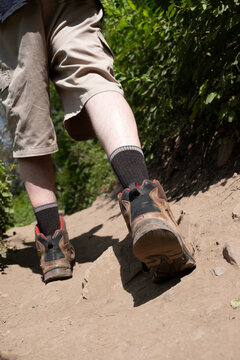 Close up of a caucasian man hiking a long a dirt trail in the mountains in Utah.  Man on a hike, focus on the old worn out hiking boot.