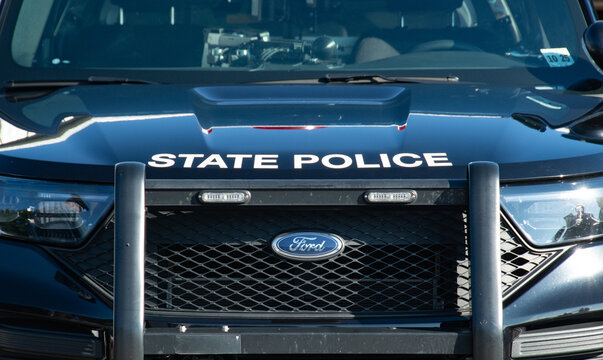 Close-up front view of a State Police patrol vehicle showing Ford badge, grille, push bumper and patrol lights, conveying authority, public safety and law enforcement readiness on duty.