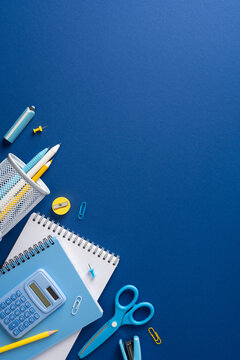 Back to school flat lay with blue stationery, calculator, notebook and scissors for study on vertical blue background with space for mockup