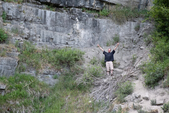 Enthusiastic middle aged caucasian man celebrates with arms up over head during a climb on Mount Timpanogos in Provo, Utah.  Stewart Falls hiking trail near Sundance.  Man on the side of a mountain.