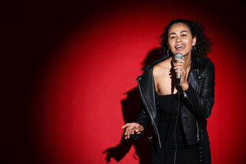 Obraz premium Professional singer with microphone performing on red background. Space for text