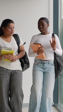 Multiethnic female students talking and walking in university hallway