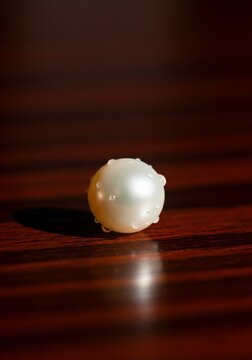 Single pearl on wooden surface