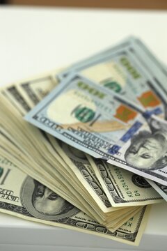 Stack of cash with various denominations placed on a flat surface in a well-lit room