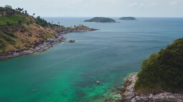 Phuket Island Bay, picturesque turquoise ocean waters meeting tropical rocky coastlines and lush green hills with kayakers enjoying the serene bay. Thailand travel and relax. Aerial view drone flight