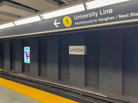 Empty Union station platform showing University Line sign and yellow tactile safety strip along track edge, Toronto July 2026