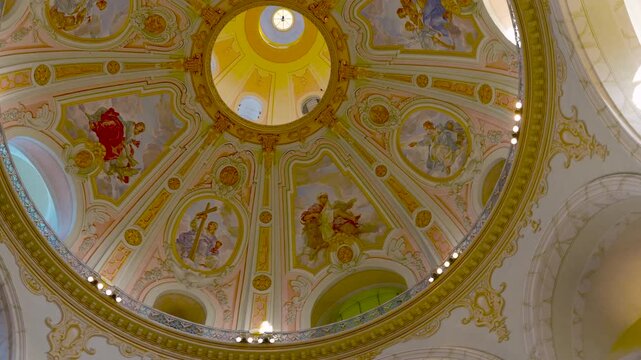 Ornate church dome with religious frescoes rotating. Low-angle view of a beautifully painted dome ceiling inside a historic cathedral, slowly rotating to showcase the intricate frescoes