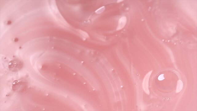 Liquid pink soap, shampoo, washing gel texture. Pearlescent surface of liquid pink fluid, background, shampoo texture, body care cosmetic, soap backdrop with bubbles top view, from above, rotating 