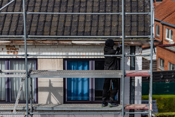 Ouvriers sur des échafaudages qui réparent une gouttière de maison © joef