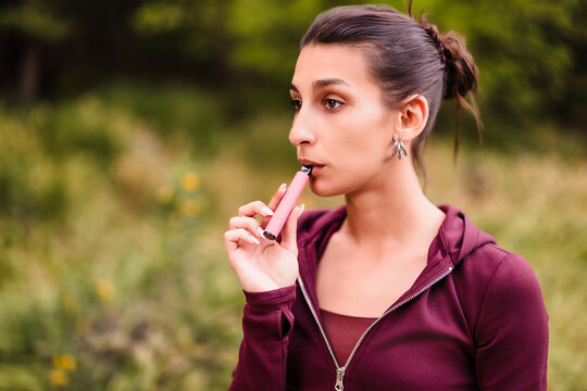 Young woman vaping e cigarette outdoors, addiction concept