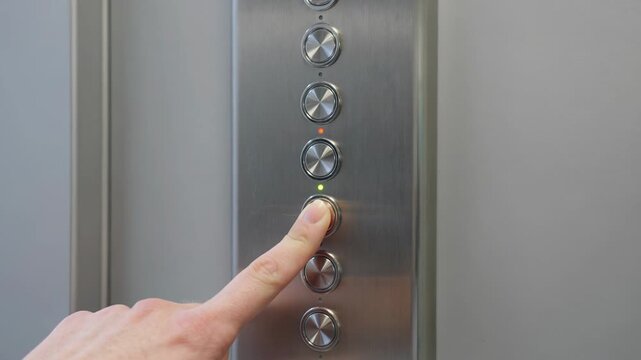 Woman pressing an elevator button on a metal control panel. Hand pushing illuminated lift switch to call transport. Modern building interior and access technology