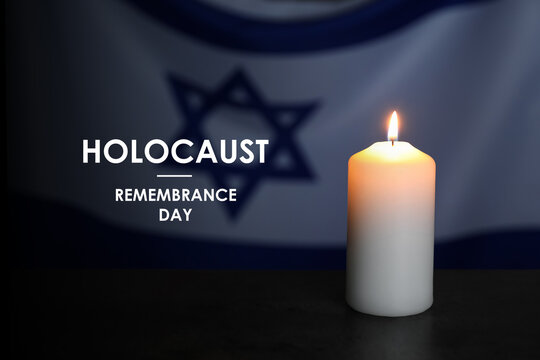 Holocaust Remembrance Day. Burning candle on table against flag of Israel