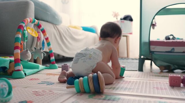 Adorable baby crawling on a play mat exploring the room