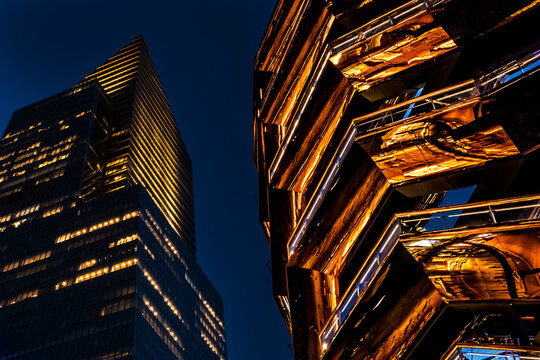 New York, NY - US - Jul 20, 2026 An impressive low-angle shot of the Vessel at Hudson Yards, surrounded by modern skyscrapers under a clear blue twilight sky, showcasing New York's architecture.