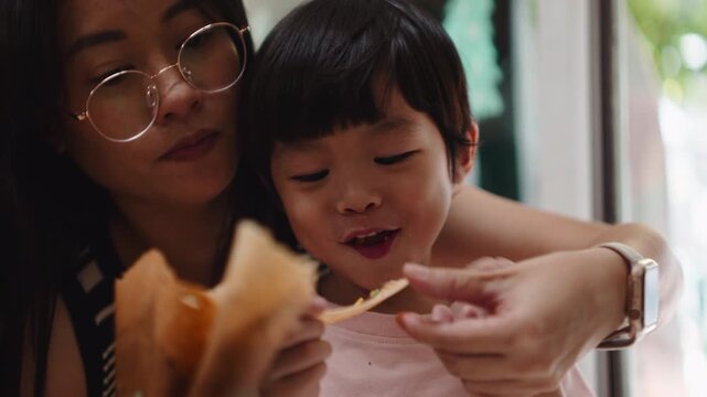 Mother and son enjoying a crispy snack together in a cafe
