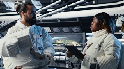 Cosmonaut fist-bumps a colleague before leaving the starship to descend on a planet, while another astronaut puts on a helmet for a human survival and colonization expedition in deep space. © DC Studio