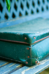 Vintage green suitcase on rustic bench for travel and nostalgia themes © Hanna