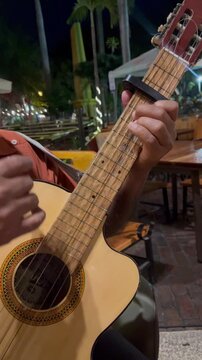 Close-up vertical shot of hands playing chords on an acoustic guitar.