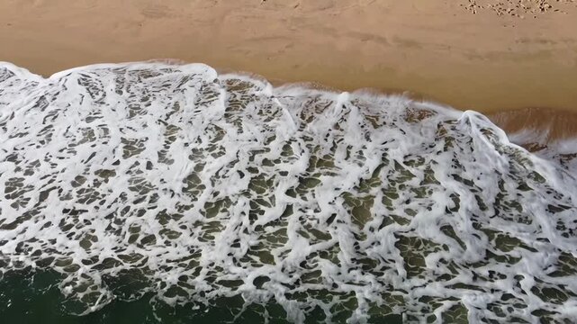 Aerial view of ocean waves crashing onto a sandy beach