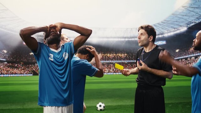 Soccer referee showing yellow card to angry player protesting during match, blue teammates complaining about match official decision, disciplinary action sanctioning.