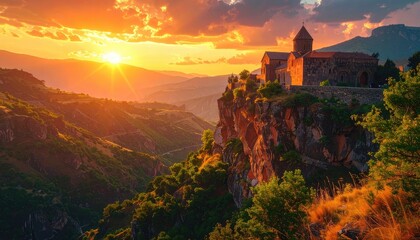 Obraz premium Ancient monastery perched precariously on a cliffside overlooking a vast mountain valley at sunset.