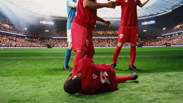 African American footballer rolling on grass after contact with opponent, risky tackle makes him fall on ground in pain, teammates protesting and asking for foul sanction after injury.