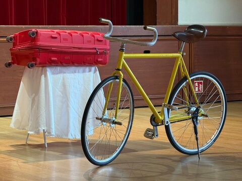 V&eacute;lo &agrave; pignon fixe jaune expos&eacute; pr&egrave;s d&rsquo;une valise rouge