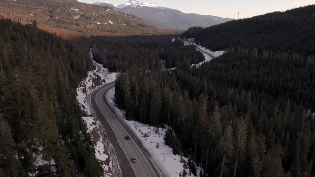 Aerial drone view of winding mountain highway through snowy Coast Mountains near Whistler, British Columbia