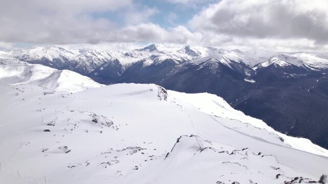 Aerial drone view of Whistler ski resort alpine terrain and snow-covered mountain peaks, British Columbia