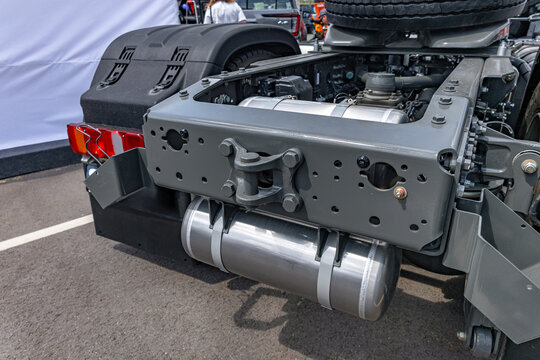 Semi truck chassis rear crossmember with towing hitch pin. Commercial cargo transport vehicle tractor frame section with aluminum air receiver tank and heavy duty engineering details view.