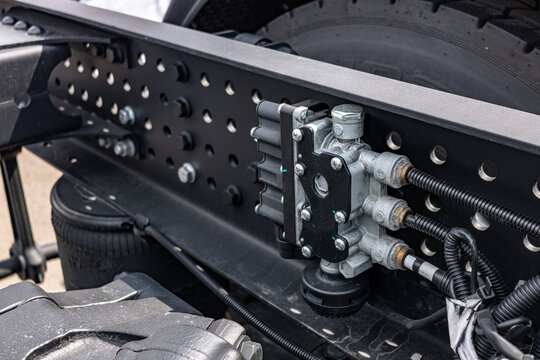Semi truck chassis EBS brake control valve valve module. Modern commercial heavy duty transport vehicle air pneumatic system component on frame with long haul tractor technical engineering details.
