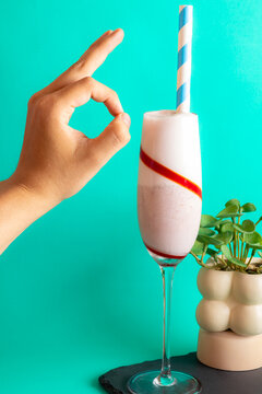Gourmet milkshake in glass with ok hand sign over turquoise background