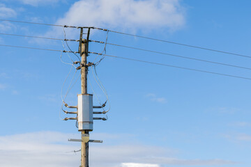 Obraz premium Pole mounted distribution transformer on a wooden electricity pole against blue sky