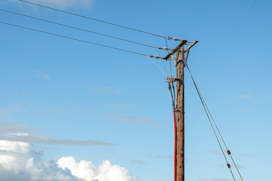 Overhead line termination pole with red cable and stay wire against blue sky