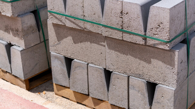 Stacked Concrete Curbstones on Wooden Pallets at Construction Site