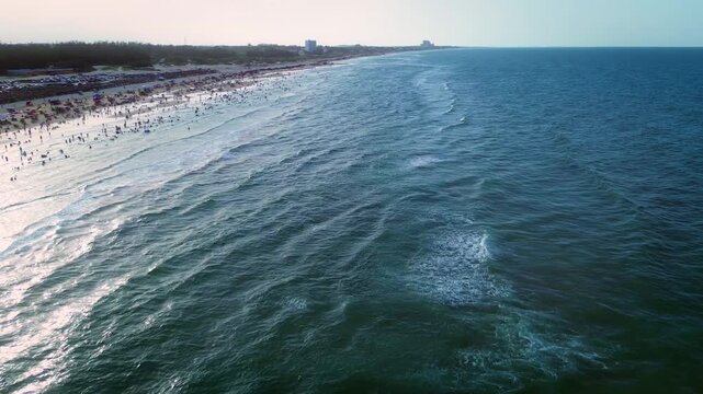 Aerial drone footage of Tampico beach with numerous tourists in water and beachfront buildings on turquoise Gulf Mexico horizon